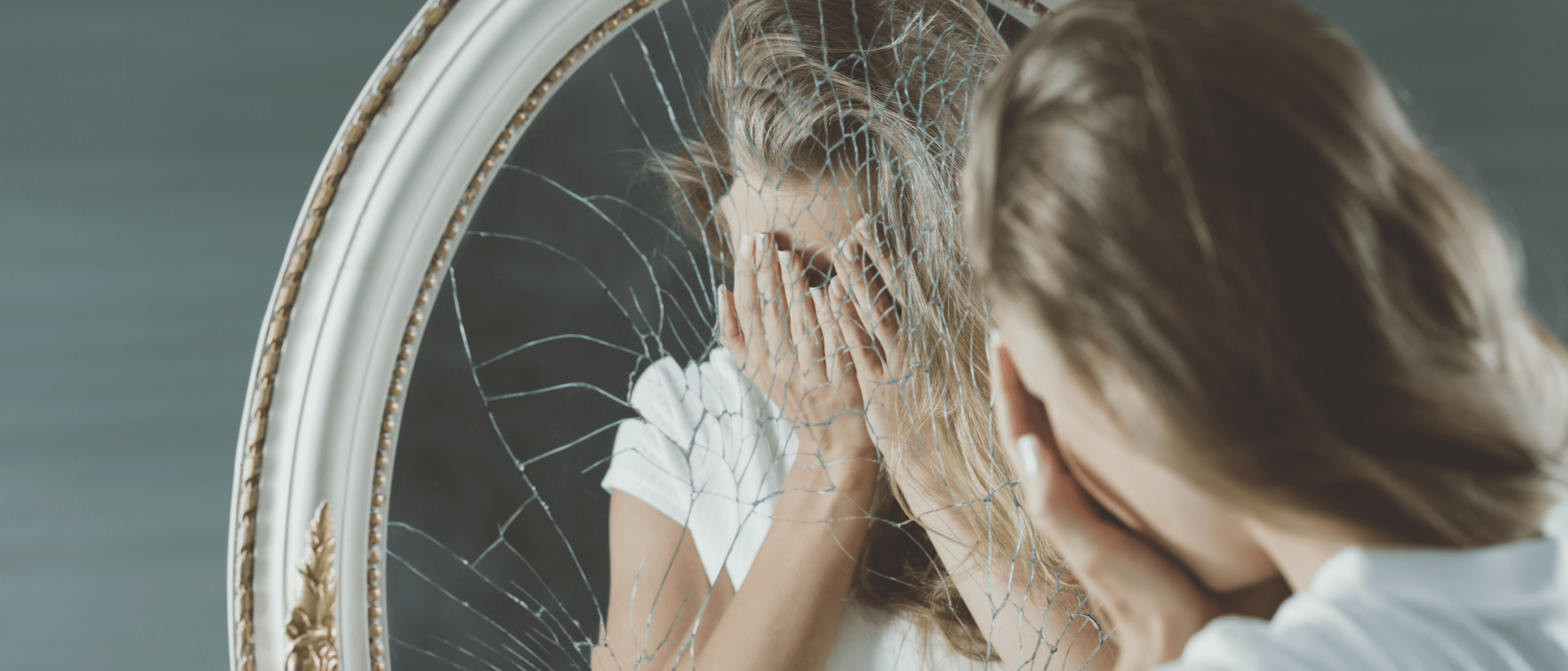 Girl suffering from anxiety looking in a broken mirror