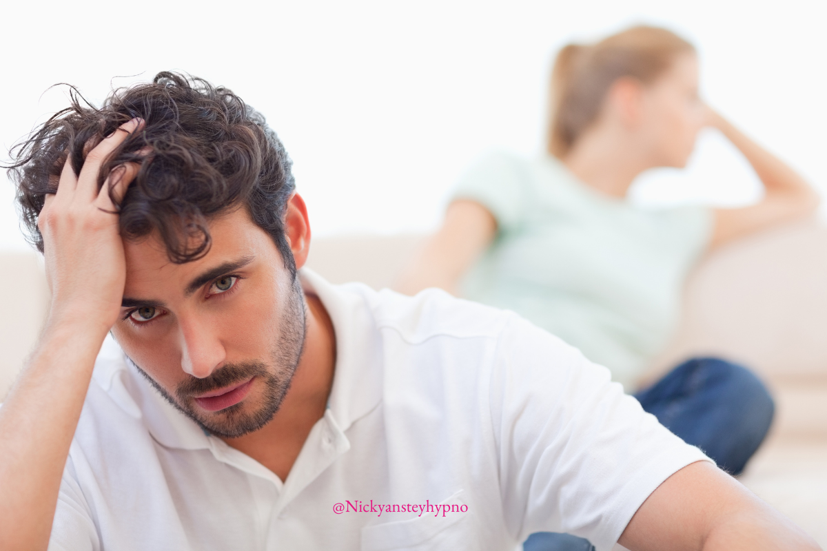 Man sitting with his hand on his head and woman in the background dispairing